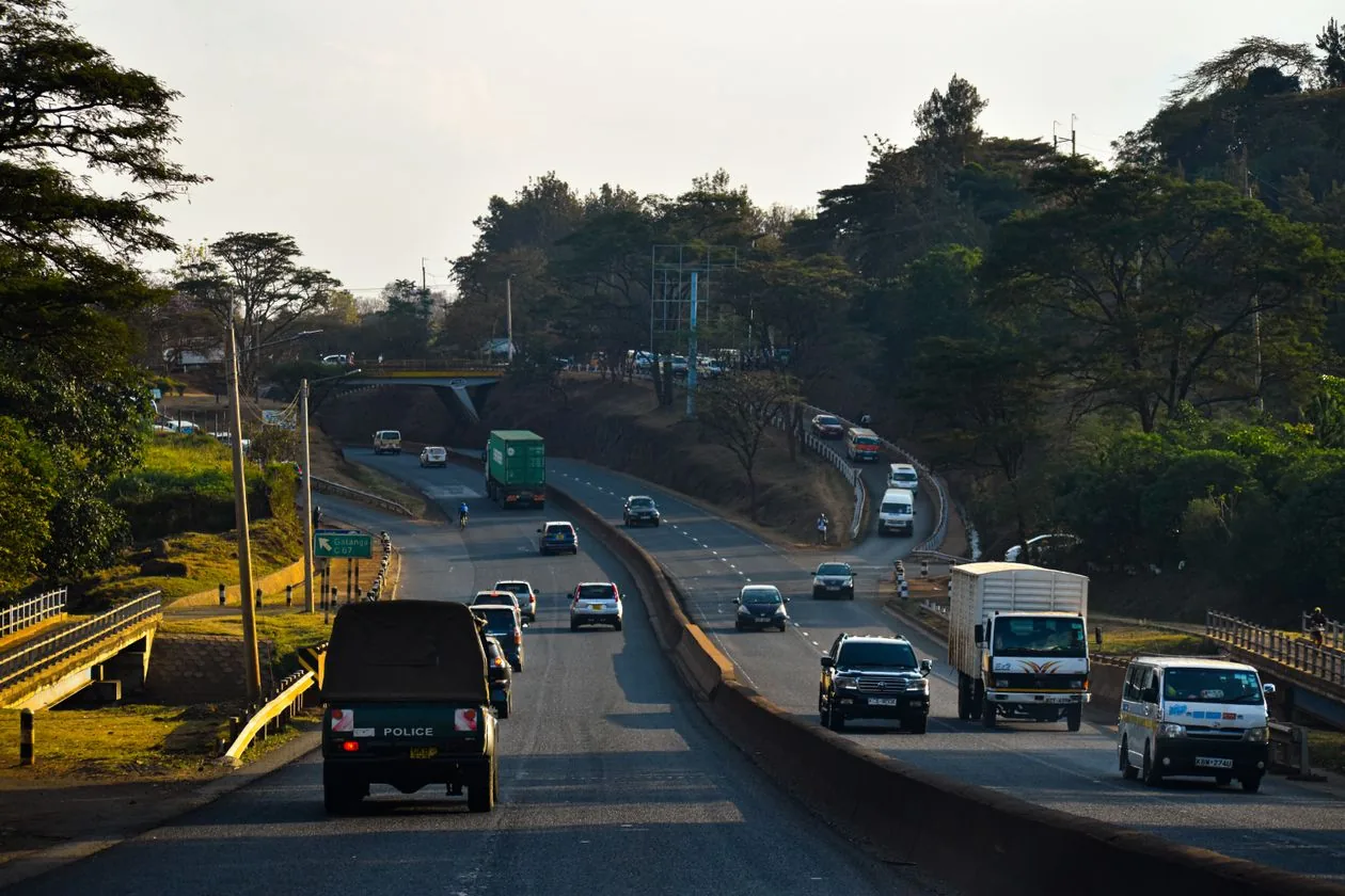 Morning staff corridor on a Nairobi highway with shuttle vans and traffic